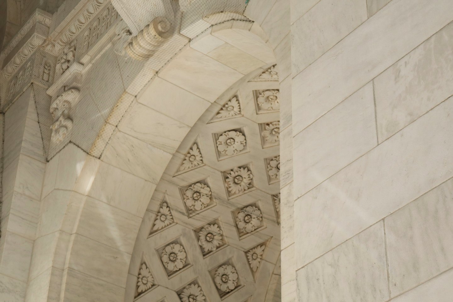 Arco in marmo finemente scolpito con rosette e volute decorative.