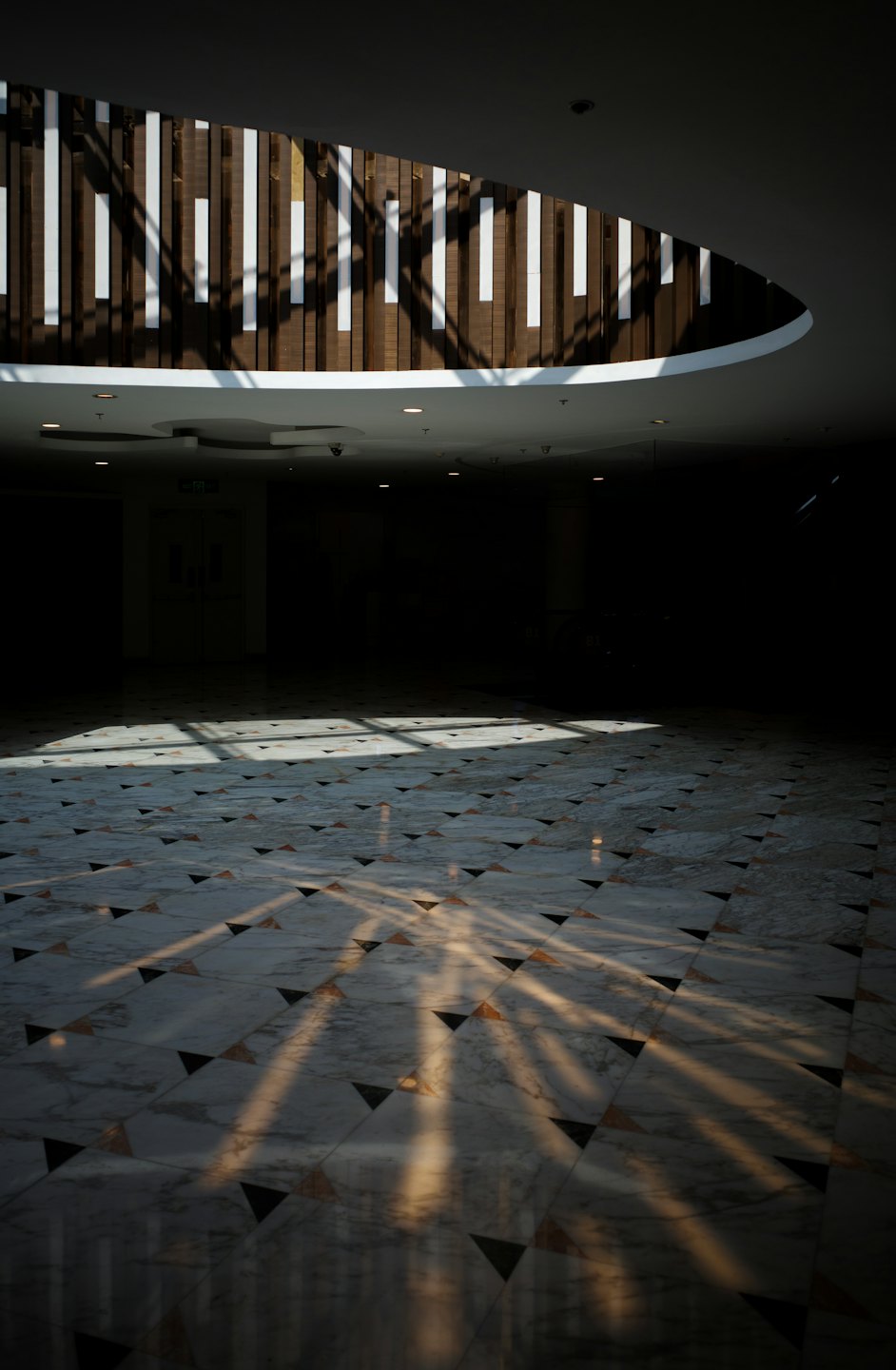 La luce del sole filtra su un pavimento geometrico in marmo di un edificio moderno.