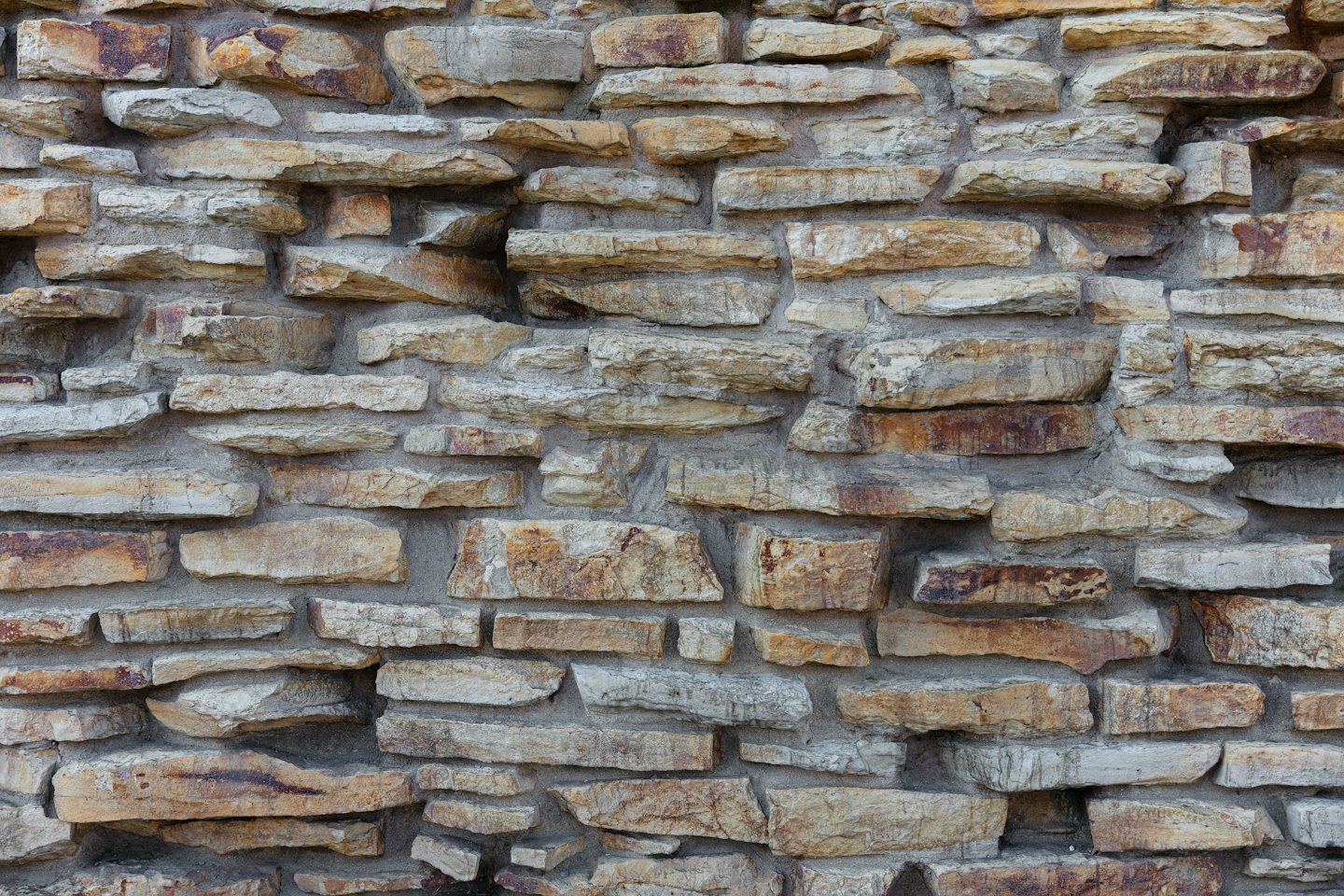 Muro in pietra naturale costruito con blocchi irregolari interconnessi.