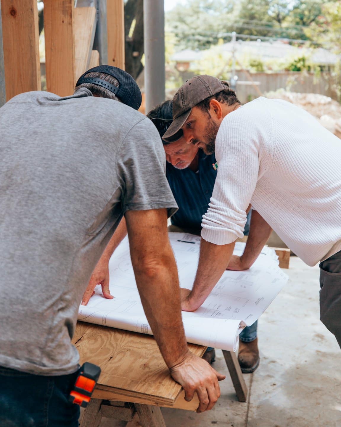 Operai edili esaminano progetti in un cantiere all'aperto.