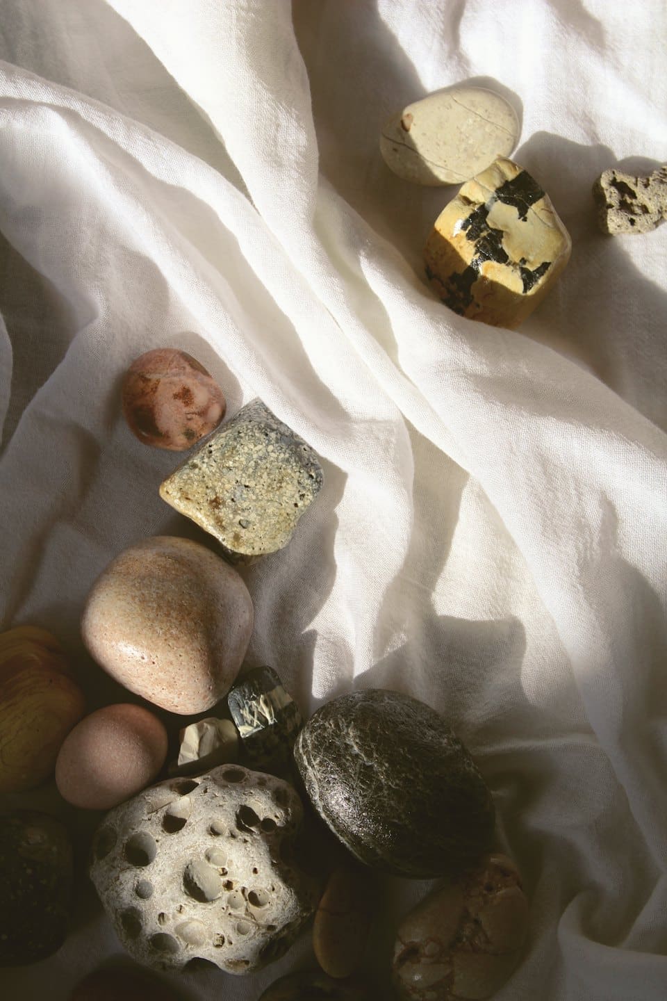 Pietre naturali di varie forme disposte su lino bianco.