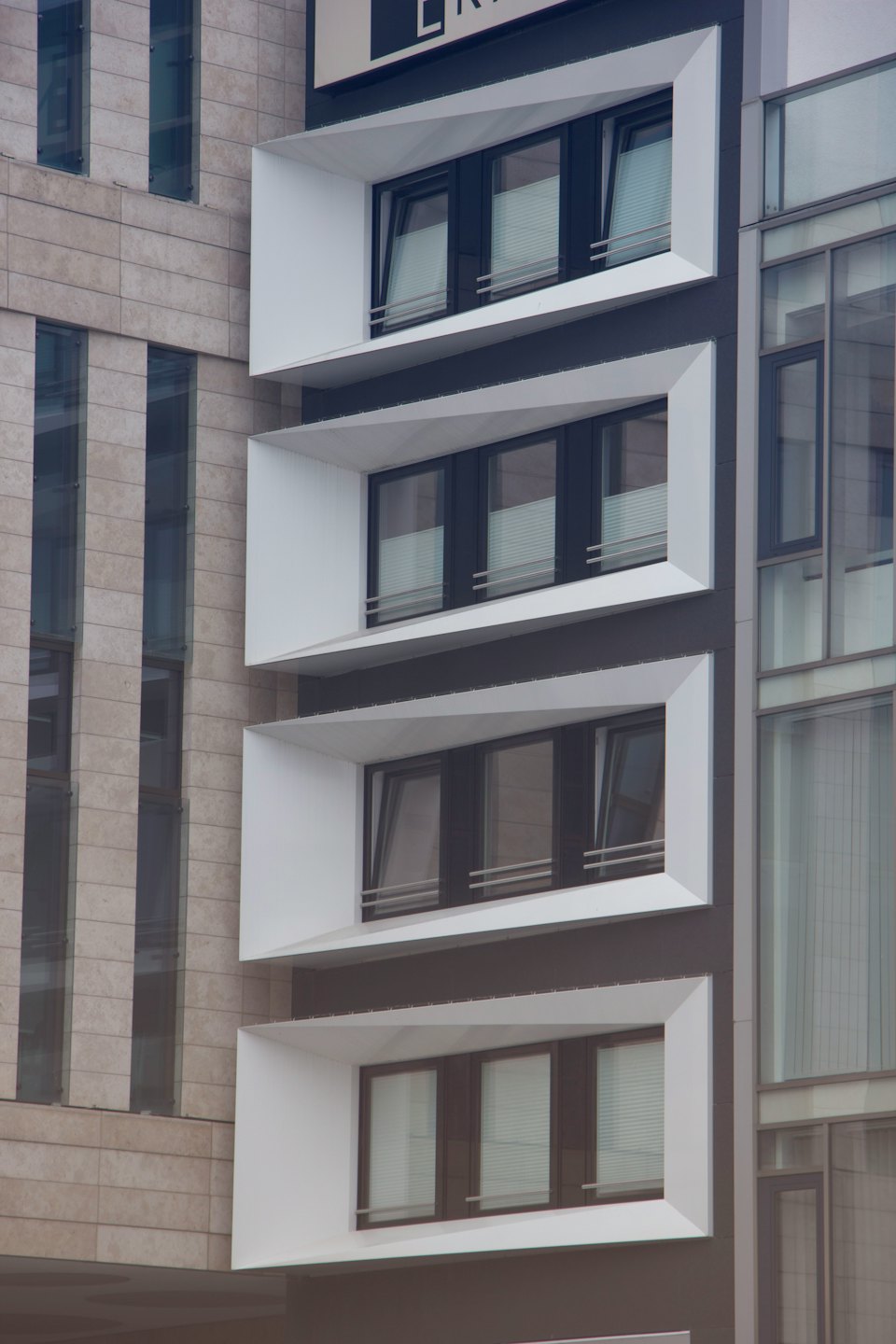 Facciata di un edificio moderno con rivestimento in pietra e finestre geometriche.
