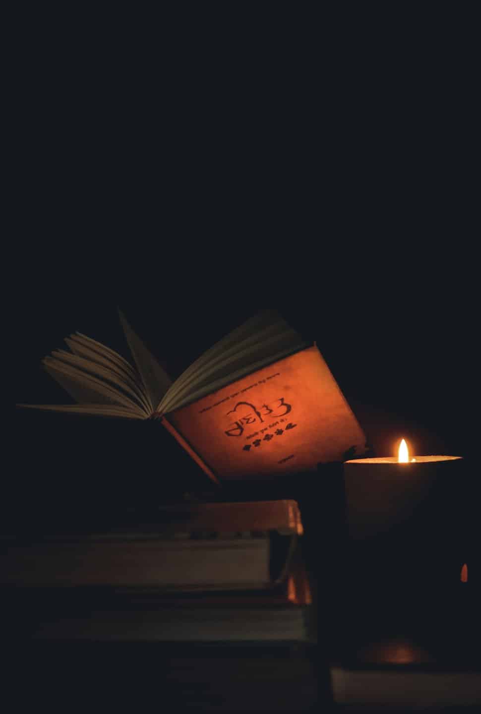 Un libro antico aperto accanto a una candela tremolante.