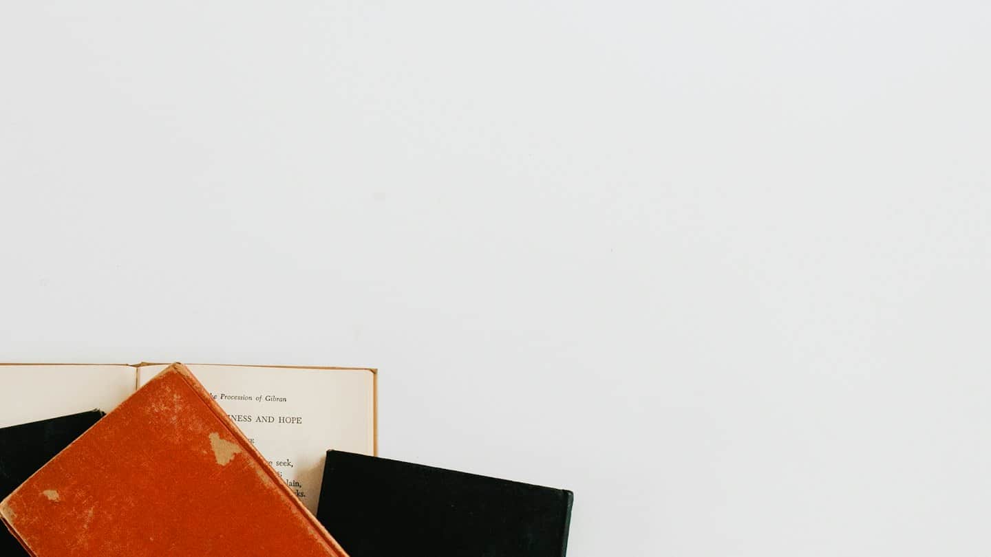 Tre libri disposti su una superficie bianca.