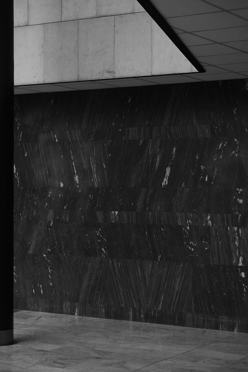 Stanza minimalista moderna con parete in marmo nero e soffitto in cemento grigio.